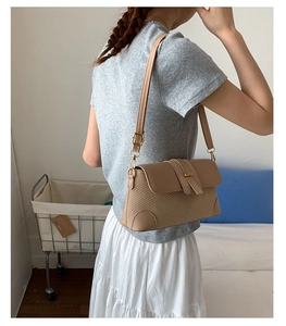 Detail of adjustable strap and khaki straw texture on a stylish crossbody bag