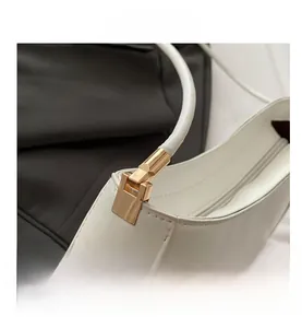 Detail of white shoulder bag featuring gold metal hardware and smooth faux leather texture