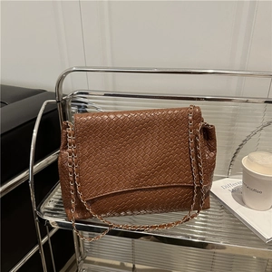 Brown woven texture shoulder bag with golden chain strap on a vintage silver cart