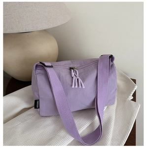 Detail view of purple nylon crossbody bag with fabric strap and brand woven label