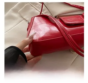 Detailed close-up of red glossy leather bag showing precise stitching and logo texture