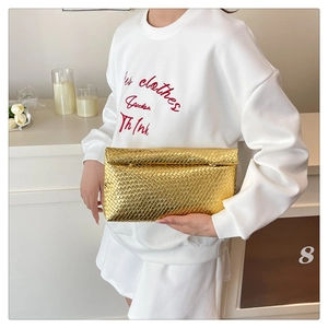 Detailed view of large gold woven clutch bag with textured metallic finish for evening