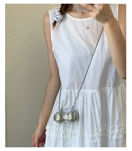 Close-up of peanut shaped crossbody bag with pearl embellishments and silver chain
