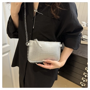 Detail of silver crocodile-embossed mini bag with metallic finish and beaded chain trim