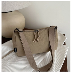 Close-up of khaki nylon shoulder bag with dual zippers and knotted cord pullers