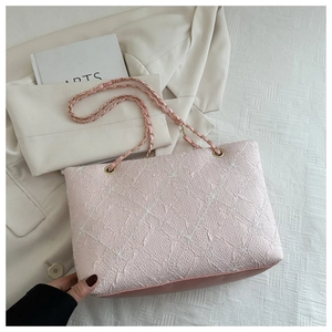 Detail of pink tweed tote bag showing quilted floral texture and gold chain straps