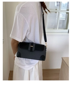 Detailed close-up of textured linen fabric stitching and golden metallic clasp on bag