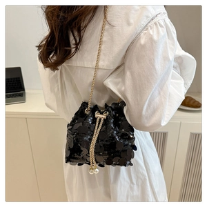 Detail of black sequin bucket bag with gold chain strap and elegant pearl charms