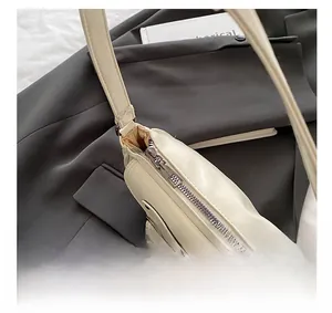 Detail showing the smooth zipper closure and side pocket on this beige faux leather bag