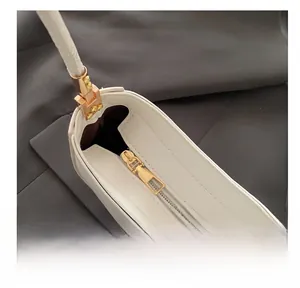 Macro detail of high-quality golden zipper and sewing on white leather crossbody bag