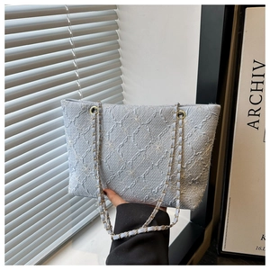 Close-up of light blue jacquard tote bag with floral texture and gold chain strap