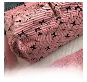 Detail of pink corduroy tote bag featuring black bow patterns and adjustable shoulder strap