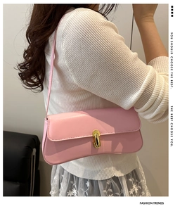 Borsa baguette rosa pallido con fibbia dorata indossata da una modella in un set moderno