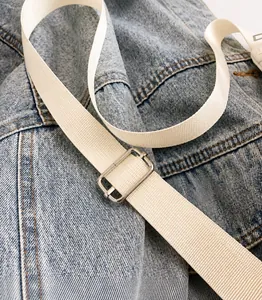 Close-up of adjustable silver metal buckle on a beige woven shoulder bag strap