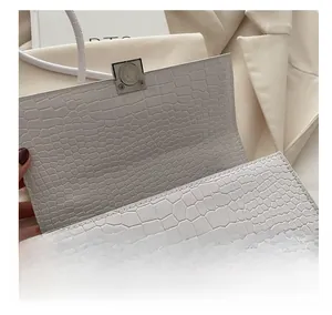 Detail view of the silver magnetic snap closure on a white crocodile texture bag