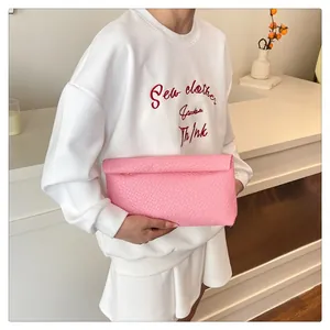 Detail of pink woven texture envelope clutch bag with embossed minimalist pattern
