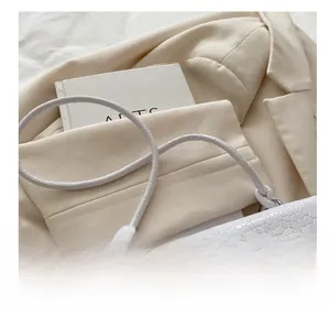 Detail shot of comfort shoulder strap with stylish knot on white crocodile pattern bag