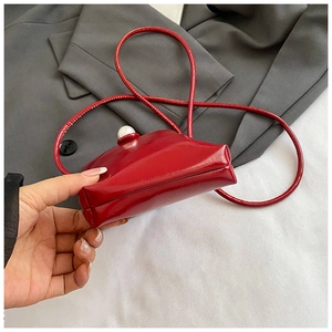 Detail of red patent leather mini phone bag with large white pearl buckle and thin strap