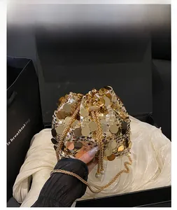 Detail of gold sequins bucket bag with drawstring closure and chain strap on silk