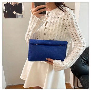 Detail of navy blue woven texture envelope clutch bag with large flap and metal hardware
