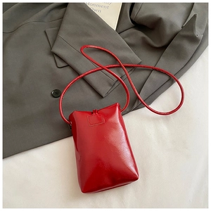 Detail of red glossy leather vertical mobile phone bag on a grey suit backdrop