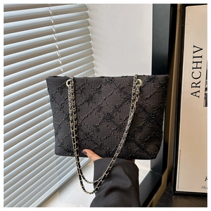 Close-up of black tweed tote bag with quilted pattern and gold chain strap detail