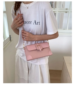 Close-up of pink textured crossbody bag with metal buckle and slim shoulder strap