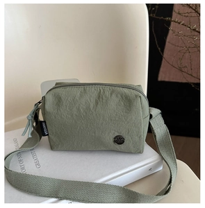 Close-up of sage green nylon shoulder bag with wrinkled texture and metal detail