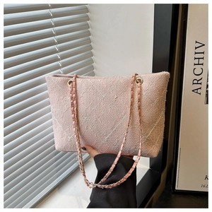 Close-up of pink tote bag showing textured jacquard fabric and golden chain strap detail
