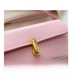 Close-up of the light pink faux leather handbag with a golden U-shaped metal buckle detail