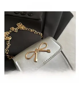 Macro shot of silver metallic leather mini bag with gold bow clasp and fine chain strap