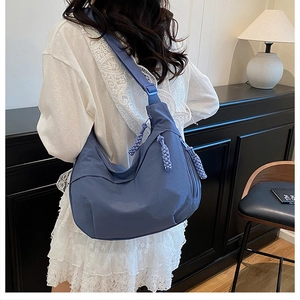 Vue détaillée du sac demi-lune en nylon bleu brume avec tirettes de zip à glands tissés