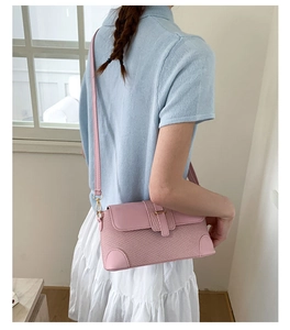 Detail of pink baguette bag showing woven grid texture and golden buckle on smooth leather
