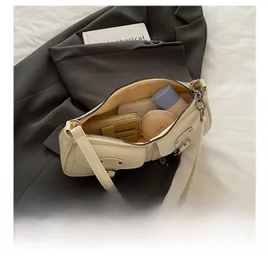 Internal capacity of off-white underarm bag showing smartphone and makeup items