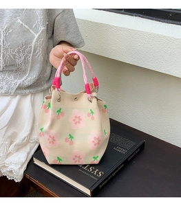 Detail of knit bucket bag with pink floral patterns and magnetic snap closure