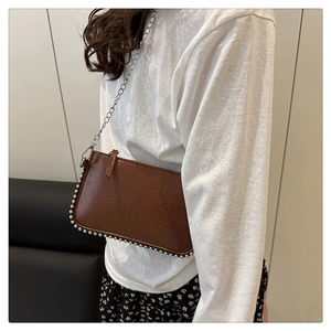 Détail d'un sac à main marron effet pierre avec bordure perlée argentée et bandoulière chaîne