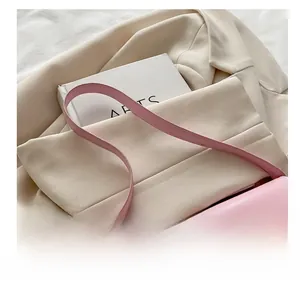 Close-up of light pink leather bag with gold metal twist lock and slim shoulder strap