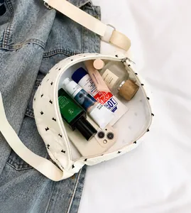 Spacious white crossbody bag with black bow patterns showing internal storage capacity