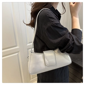 Detail of silver patent leather shoulder bag with metallic logo bar and slim strap
