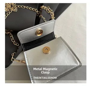 Detail of the golden magnetic snap closure on a silver textured leather saddle bag