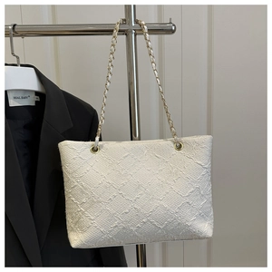 Detailed view of white woven texture tote bag with elegant gold chain and leather strap
