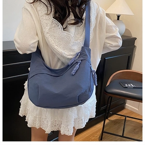 Gros plan du sac demi-lune en nylon bleu avec tirette en corde et poche latérale