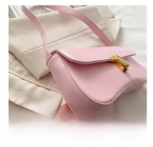 Detail view of pink leather underarm bag with golden twist lock and precise stitching