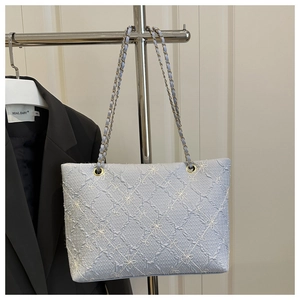 Detail of light blue tote bag featuring 3D textured fabric and white floral embroidery