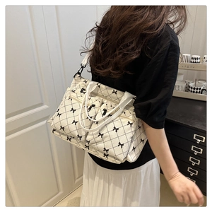 Side view of white corduroy tote bag with black bow print and multiple zip pockets