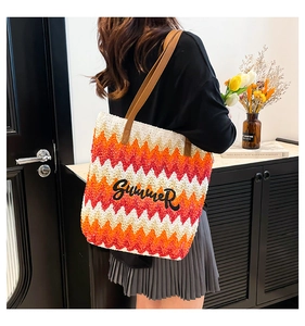 Macro detail of multicolored woven straw tote bag with Summer embroidery and leather handles