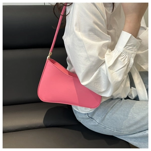 Close-up of rose pink hobo bag with gold hardware worn by model in white shirt