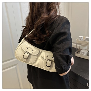 Detail of off-white leather baguette bag with retro buckle pockets on a model