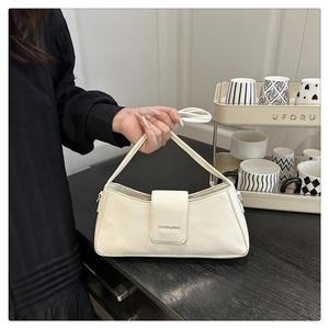 Detailed view of the minimalist white patent leather underarm bag with brand lettering