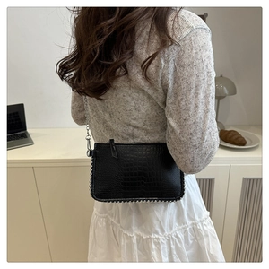 Détail du sac à main noir motif crocodile avec bordures perlées argentées et chaîne